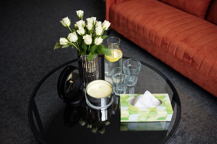 Stół z kwiatami i szklankami - sofa w tle